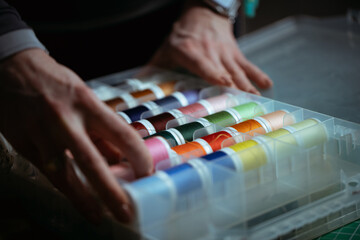 Detailed close-up photograph showing hands guiding fabric through an industrial sewing machine. The image captures the precision and craftsmanship involved in textile production and tailoring. Ideal f