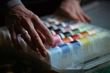 Detailed close-up photograph showing hands guiding fabric through an industrial sewing machine. The image captures the precision and craftsmanship involved in textile production and tailoring. Ideal f