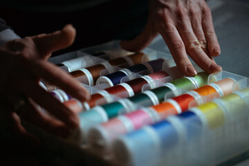 Detailed close-up photograph showing hands guiding fabric through an industrial sewing machine. The image captures the precision and craftsmanship involved in textile production and tailoring. Ideal f