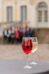Red and white wine glasses near the castle and background people 