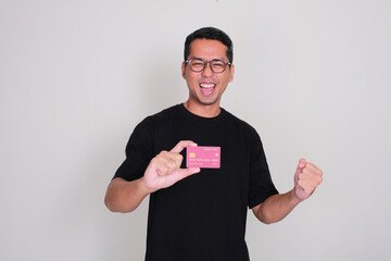 A man clenched fist showing excited expression while holding a credit card