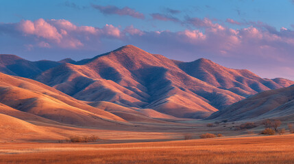 Sunset over desert mountains with soft pink and blue sky, serene evening landscape with textured hills for travel or natural design