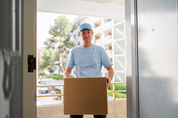 A male courier in a blue uniform with a parcel in his hands.