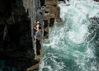 Climber tackling a challenging deep water solo route on a cliff in Pembrokeshire, Wales