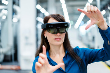 Businesswoman with augmented reality eyeglasses making finger frame at industry