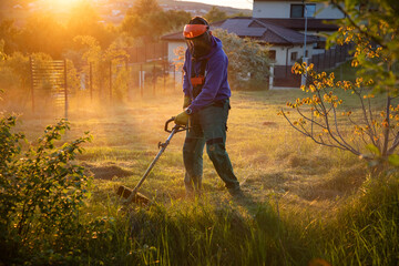 man mowing the grass with a lawn mower. Garden work at sunset