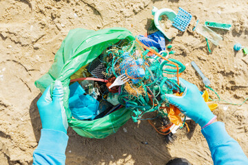 Person collecting ocean waste on a beach during a cleanup effort