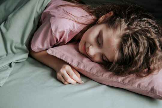 Girl sleeping peacefully with a baby tooth under her pillow, symbolizing childhood and the tooth fairy tradition