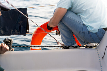 Sailor adjusting lifebuoy on sailboat during sea navigation