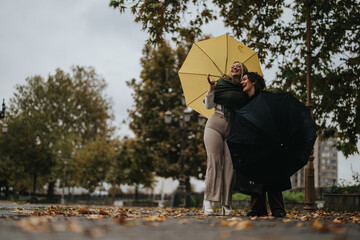Two cheerful individuals share a joyful moment outdoors on a rainy autumn day, smiling with umbrellas in a park filled with fallen leaves and vibrant green trees, embracing the rainy season together.