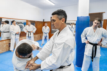 Karate instructor showing arm lock technique to student in dojo