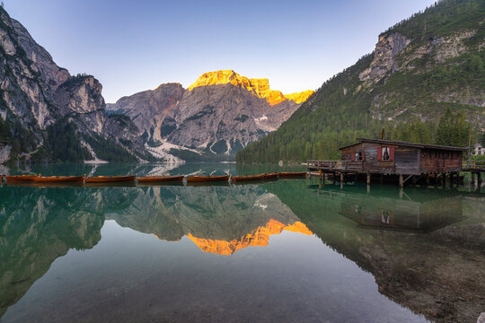 Reflection of Croda del Becco mountain in Pragser Wildsee lake by log cabin at Dolomites, Alto Adige, Italy