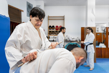 Obraz premium Senior martial arts instructor demonstrating jo staff technique on student
