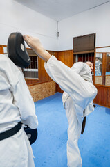 Karate athletes training kicking and blocking techniques in dojo