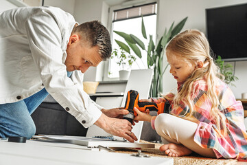 Father and daughter assembling furniture together at home