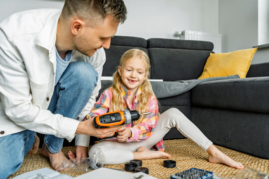 Father and daughter assembling furniture together at home