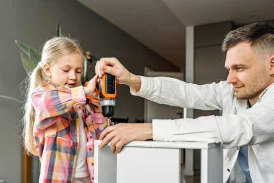 Father and daughter assembling furniture together at home