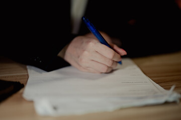 Close-up of a form being filled with a blue pen, representing administrative tasks and office...