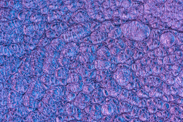 Vibrant silver inks emit neon waves in purple light creating an abstract texture