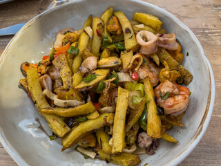 Traditional food from Mallorca: fried potatoes with seafood and green onions, top view