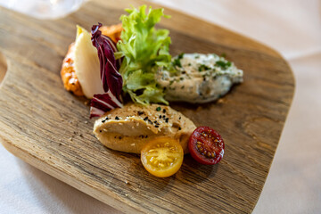 Appetizer of hummus, cherry tomatoes and salads on a wooden board