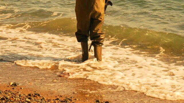 Metal detector beachcombing treasure Treasure hunter in waders searches beach with metal detector for treasure finds today