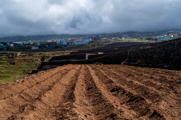 A field of dirt with a cloudy sky in the background. The sky is overcast and the field is empty
