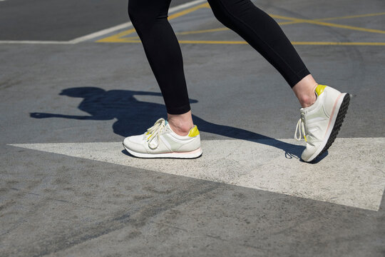 close up of a woman runner with arrow painted on the road.