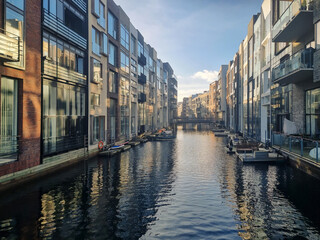 Copenhagen - Modern residential buildings line a calm canal in Sluseholmen, Copenhagen, Denmark. The contemporary architecture is reflected in the water under a clear sky, showcasing urban living.