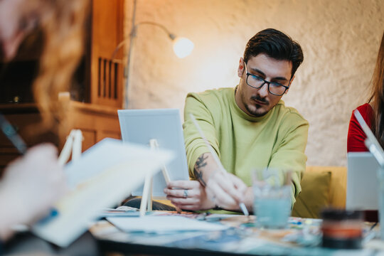 People are drawing and painting together in a relaxed and creative setting. The scene evokes teamwork, friendship, artistry, and shared hobbies, highlighting a moment of concentrated creativity.