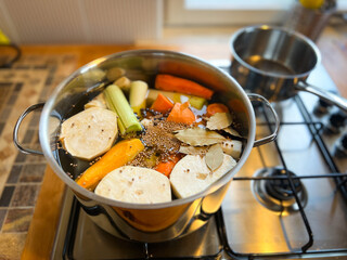 Fresh cut vegetables and spices in a pot, cooking soup on a stove, first stage, top view, preparing vegetarian soup, soup in progress, rustic style kitchen.