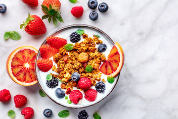 Granola with yogurt and fresh fruit. Organic gourmet muesli, overhead flat lay shot on a marble table, with a copy space