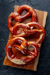 Pretzel or Bretzel, traditional German beer snack, a salty wheat bread, shot from the top on a wooden board
