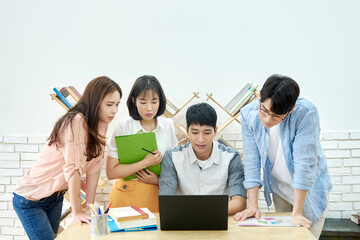Young Asian Men and Women Collaborating on Project Around Laptop in Modern Study Room