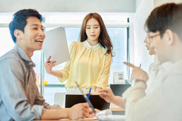 Fototapeta premium Young Asian Woman Leading Team Meeting with Colleagues in Modern Office