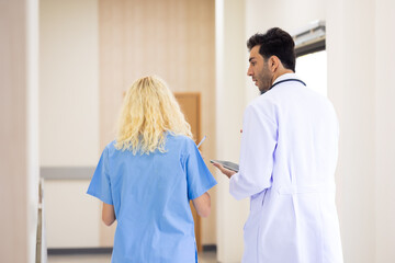 Back view : Multi-ethnic healthcare workers in hospital. nurse and doctor walking in corridor and ...