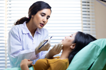 Fototapeta premium Facial aesthetics surgery treatment : Plastic (Cosmetic) Surgery Center : Brazilian hispanic female Doctor preparing Asian female patient for cosmetic surgery in clinic