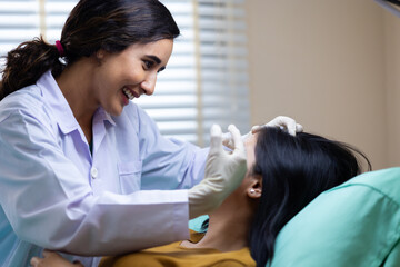 Obraz premium Facial aesthetics surgery treatment : Plastic (Cosmetic) Surgery Center : Brazilian hispanic female Doctor preparing Asian female patient for cosmetic surgery in clinic