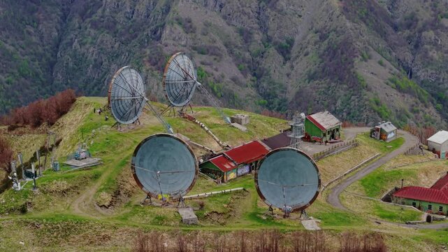 Old radar station on a green mountain ridge, peaceful and remote aerial view