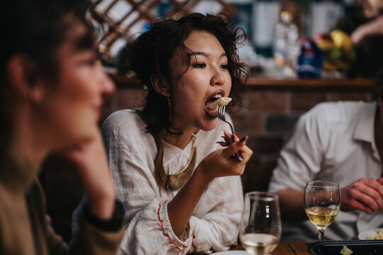 A young woman eating at a lively bar setting, surrounded by friends enjoying the moment. The atmosphere suggests a casual gathering or dinner, emphasizing friendship and togetherness.
