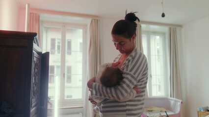 Mother breastfeeding her baby while standing in the bedroom, comforting and nurturing, intimate...