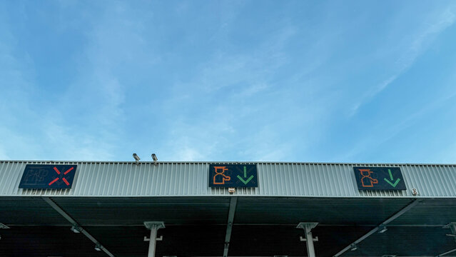 Beneath an ethereal azure sky, cryptic signs on the rooftop herald urban symphony, invoking Dia de los Muertos' mystery