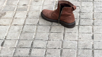 Lonely leather boot on cobblestone whispers wanderlust tales, evoking lost-and-found themes and...