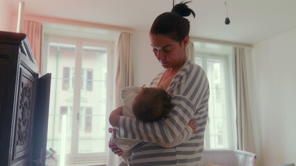 Mother breastfeeding her baby while standing in the bedroom, comforting and nurturing, intimate...