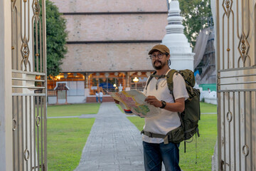 Asian male solo traveler exploring Thailand with a map in hand - concept of independence, adventure, and Southeast Asia discovery
