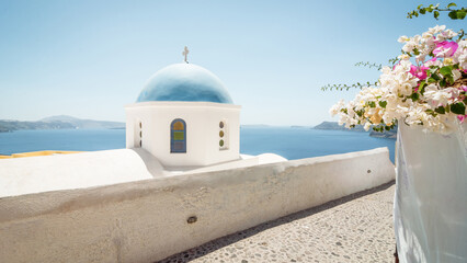 Church dome and walls on the cliff of Santorini island, Aegean sea and Cyclades islands in the background.