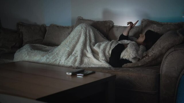 Innovative Evening: Woman Lying on the Couch, Using a Cutting-Edge Invisible Gadget Embedded in Her Contact Lenses
