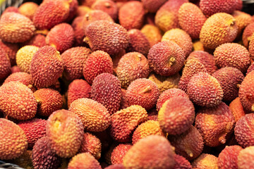 A close up view of a large pile of fresh lychees in a woven basket