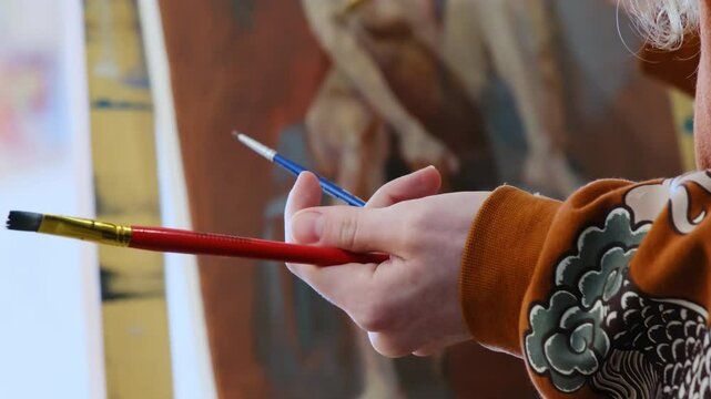 Master holds special tools in hand creating figure in hall. Creator learns to paint picture and hones skills in working on details applying brushes