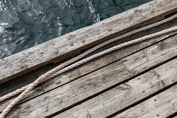 Weathered wooden pier with coiled rope and ocean water